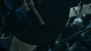 Ortaçağ savaş Reenactment. Savaşçı saldırı korumaları ve tahta kale sivil şiddet kabilesi. Balta, kılıç ve kalkanlar ile mücadele.