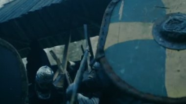 Ortaçağ savaş Reenactment. Savaşçı saldırı korumaları ve tahta kale sivil şiddet kabilesi. Balta, kılıç ve kalkanlar ile mücadele.