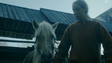 Ortaçağ Köyü hayat canlandırma. Ahşap kalenin avlusunda, Genç kadın bir at açar..