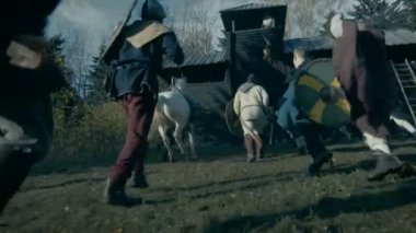 Ortaçağ savaş Reenactment. Vahşi savaşçı kabilesi tahta kale saldırıları, kapılarından kaçıyorlar. Balta, kılıç ve kalkanlar ile silahlı.