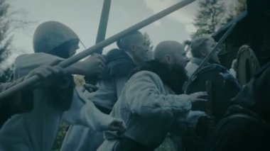 Büyük ölçekli ortaçağ savaş Reenactment. Şiddet kabilesi savaşçıları saldırı tahta kale duvarı, onlar tırmanmaya merdivenler, gardiyanlar deneyin Fortification.They mücadele eksenleri, kılıç, mızrak, ok ve kalkanlar savunmak.