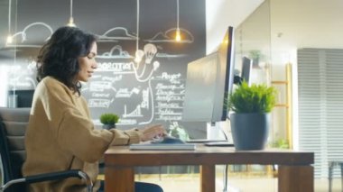 Yaratıcı kurumunda güzel genç kadın kameramanların görüntüleri Video ve ses düzenleme onun kişisel bilgisayarda çalışıyor. Arka planda onun iş arkadaşı ve yazı tahtası çizilmiş planları ile.