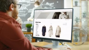 Web Tasarımcısı Web sitesi Online perakende giyim mağazası için çalışır. O ve arkadaşları şık yaratıcı ajansı Studio planları ve çizimler kaplı tahta duvar ile çalışmak.