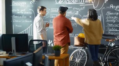 Kadın geliştirici ile Tablet bilgisayar görüşmeler akmak ve Proje Yöneticisi ile bir planlayıcısı olarak Blackboard duvar kullanıyorlar. Şık yaratıcı ofiste çalışmak.