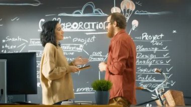 Erkek proje yöneticisi tutan Tablet bilgisayar erkek geliştirici ile konuşur, Blackboard duvara çizilen proje planını tartışmak. Yaratıcı ajansı çalışıyorlar.