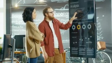 Erkek proje yöneticisi tutan toplantı istatistiksel grafikler ve etkileşimli beyaz tahta Touchscreen aygıt üzerinde gösterir. O şık yaratıcı kurumunda çalışıyor.