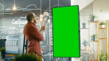 İnteraktif beyaz tahta ile Mock-up bakar erkek geliştirici yeşil ekran. O bir sorun çözüm üzerinde düşünme onun sakalı yumuşatır. Arka planda yaratıcı Office Project ile kara tahta duvar ile çizilmiş planları.