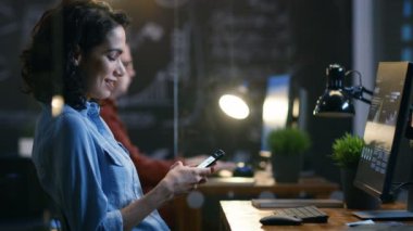 Güzel kadın yatırımcı kullandığı cep telefonu, yazılı mesajlar, Smiling.In arka plan yaratıcı ofis çalışanı olan e-postaları.