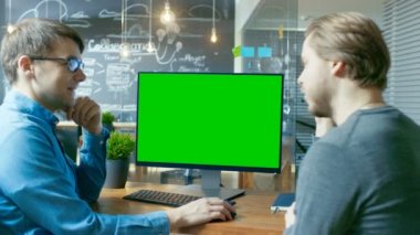 İki ofis çalışanları ilgili tartışma, Danışma standları proje var Mock-up ile kişisel bilgisayar ekran yeşil. Onlar yaratıcı ofis ortamında iş.