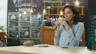 Cafe içki içecek ve seçtikleri Her cep telefonu için bir ileti yanıt kadar güzel bir kadın. Arka plan şık kahve evin içinde / kuruluş.