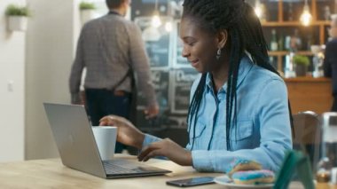 Çekici genç kadın şık kahve evinde otururken bir dizüstü bilgisayarda çalışır.