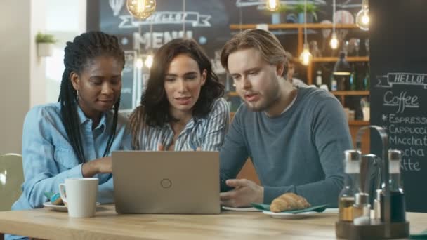 Трое Молодых Людей Кофейне Работают Над Ноутбуком Разговаривают Заднем Плане — стоковое видео