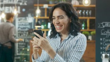 Kafede oturan güzel kadın. İyi haber onun Smartphone ve yapar 