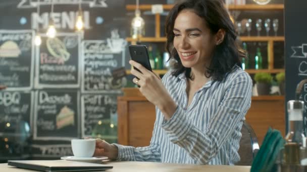 Mulher Bonita Senta Café Usa Smartphone Ela Sorri Enquanto Navega — Vídeo de Stock