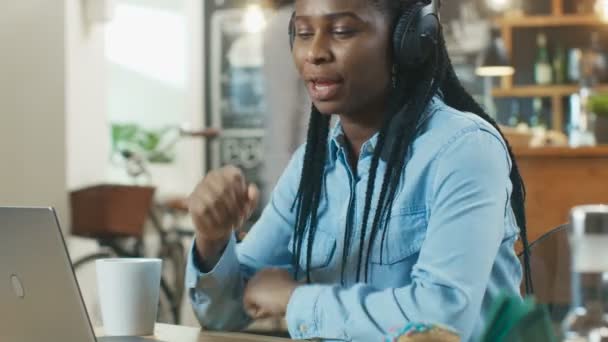 아프리카계 미국인 여자는 그녀의 휴대용 퍼스널 컴퓨터와 헤드폰 커피가 음악을 — 비디오