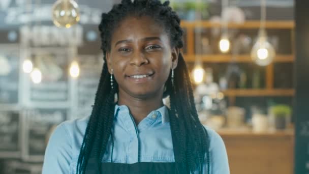 フォーカス 背景彼女スタイリッシュなコーヒー家に輝くライトの中に歩いて美しいアフリカ系アメリカ人カフェ オーナー — ストック動画