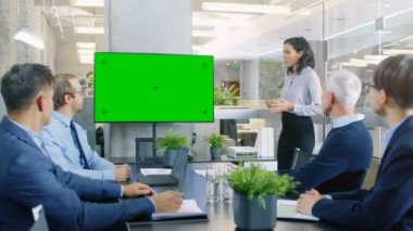 Güzel iş kadını rapor verir / sunum toplantı odasında iş iş arkadaşları için o duvar Tv ile yeşil Chroma anahtar perde ile etkileşim kurar.