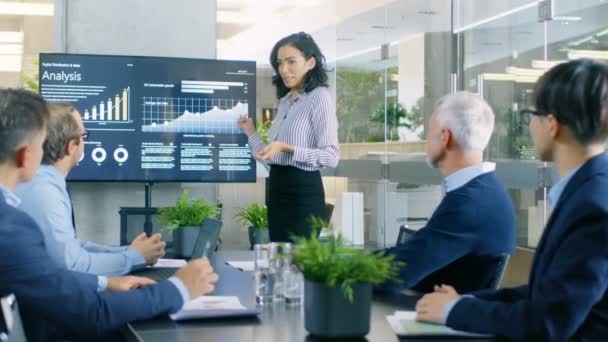 美丽的女实业家给她的商务同事在会议室的报告 她显示图形 饼图和公司在墙上电视的增长 — 图库视频影像