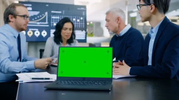 会议桌上带绿色色度键屏幕的会议室笔记本电脑 在后台业务人员有重要的讨论 — 图库视频影像