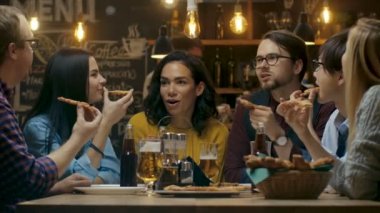 Bar / Restoran grubu farklı gençlerin yemek Pizza pasta grafiğin dilimlerini. Onlar konuşmak, espri ve şık bu işyerinde iyi eğlenceler.