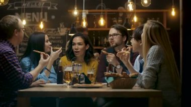 Bar / Restoran grubu farklı gençlerin yemek Pizza pasta grafiğin dilimlerini. Onlar konuşmak, espri ve şık bu işyerinde iyi eğlenceler.
