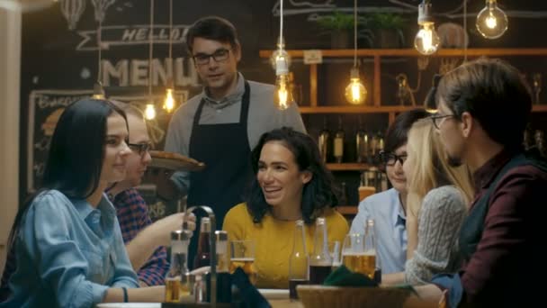 Der Kellner Serviert Einer Vielfältigen Gruppe Hungriger Und Glücklicher Freunde — Stockvideo