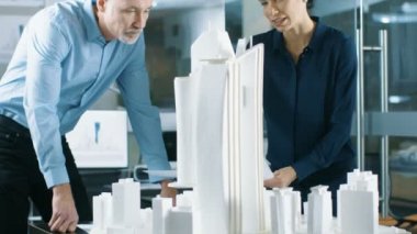 İki profesyonel erkek ve dişi mimari mühendis iş planları ve yapı modeli tasarımı için kentsel tasarım projesi.