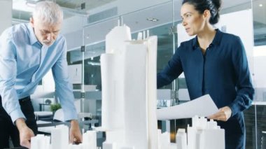 İki profesyonel erkek ve dişi mimari mühendis iş planları ve yapı modeli tasarımı için kentsel tasarım projesi.