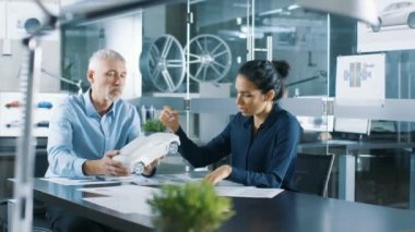 Deneyimli Otomotiv Tasarımcısı ve bir konsept araba modeli prototipin, o ve tasarım düzeltmeler yapma Perfecting ile kadın mühendis çalışır. Onlar bir şık, parlak, Modern ofis iş.