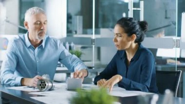 Deneyimli erkek ve kadın Endüstri mühendisleri tartışma, onlar bir makine bileşen tasarım çalışmaları var. Onlar Office bu şık ve Modern arıyorsunuz.