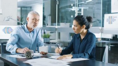 Deneyimli erkek ve kadın Endüstri mühendisleri tartışma, ayarlama yapma ve mükemmelleştirmek parçaları, onlar bir makine bileşen tasarım çalışmaları var. Onlar Office bu şık ve Modern arıyorsunuz.