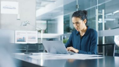 Masa İşleri 'nde dizüstü bilgisayarda oturan güzel kadın veri analisti. Modern ofis ortamında şık bir kadın..