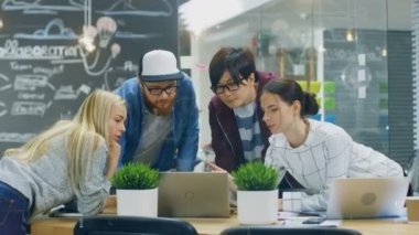 Genç kadın ve erkekler geliştiriciler farklı takım dizüstü kullanarak takım toplantısı var. Parlak Modern ofis ortamında güzel genç insanlar.