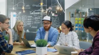 Takım lideri gösterir belge ve evrak geliştiriciler yetenekli genç, bir gruba tartışma toplantı masasında başlıyorlar. Şık ofis ortamında yaratıcı insanlar.
