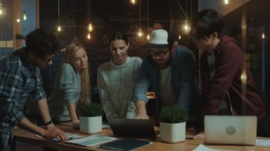 Geç gece genç ekibindeki yaratıcı geliştiriciler toplantı tablo, fikirlerini tartışıyor ve yeni kavramlar, beyin fırtınası var. Modaya uygun Office ortamında şık insanlar.