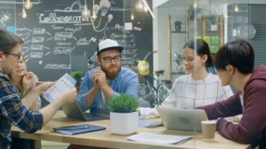 Toplantı tablo, fikirlerini tartışıyor ve yeni kavramlar otururken takım genç yaratıcı geliştiriciler var beyin fırtınası oturumunun. Modaya uygun Office ortamında şık insanlar.