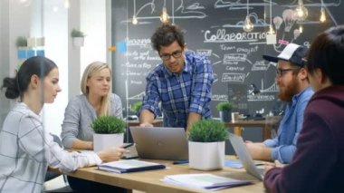 Karizmatik takım lideri Laptop yetenekli genç geliştiriciler farklı bir grup için gösterir, tartışma toplantı masasında başlarlar. Şık ofis ortamında yaratıcı insanlar.