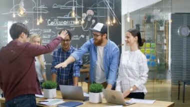Yaratıcı geliştiricilerin çeşitli takımız başarılı ortaklık jest bina. Mutlu başarılı genç insanlar şık ve Trendy ofis ortamında giyinmiş.