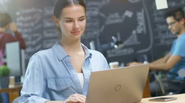 Genç kadın yaratıcı tasarımcı bir dizüstü bilgisayarda çalışır. Ben arka plan takım yaratıcı Office ortamda yetenekli insanların.