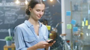 Genç kadın büyüleyici Smartphone meşgul yaratıcı Office şık yetenekli insanlarla ayakta iken kullanır.