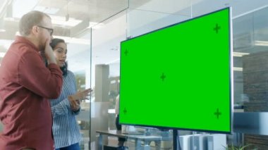 Erkek ve kadın konferans salonunda Mock-up Chroma anahtar yeşil ekran Tv hakkında tartışma var.