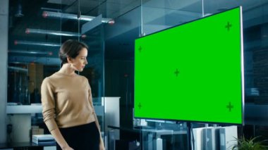 Gece geç saatlerde Mock-up Chroma anahtar yeşil ekran Tv konferans salonunda güzel beyaz kadın bakar.