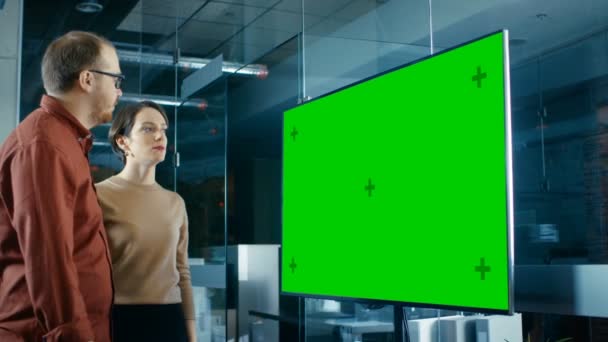 夜遅くの会議室で男性と女性の専門家はモックアップ クロマ キー緑画面テレビに関するディスカッションを実施します — ストック動画