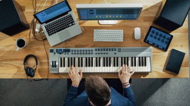 Üstten Görünüm onun stüdyosunda bir müzikal klavye üzerinde oynarken müzik yaratmak bir müzisyen. Sunny ve hoş görünümlü stüdyosunda olduğunu.