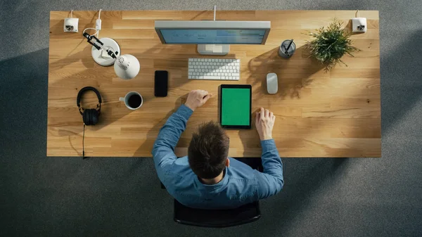 彼のデスクトップ コンピューターに入力してソフトウェア エンジニアの平面図です タブレット コンピューターとテーブルの上に横たわる緑色の画面で Smarphone — ストック写真