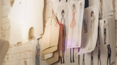 Duvara sabitlenmiş moda çizimleri ve skeçler, duvarda asılı şablonları.