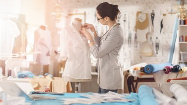 Güzel kadın moda, tasarımcı, terzilik manken, ayarlama bluz ile çalışma. Onun stüdyom Bright ve Sunny, mankenler ayakta etrafında, giysi asılı, renkli kumaşlar yalan masada.