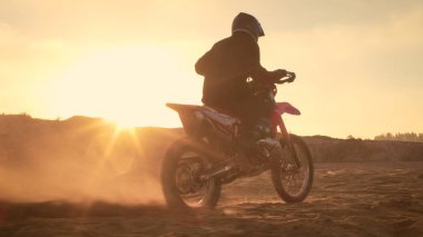 Fmx motosiklet binici tam gaz kolu katlanmış ve Sandy Off-Road yolda sürme başlar. Doğal günbatımı.