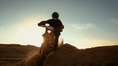 Dune üzerinde sürüş profesyonel motokros motosiklet binici ve Off-Road parça aşağı daha fazla. O gün batımı ve parça dumanla kaplı / sis.