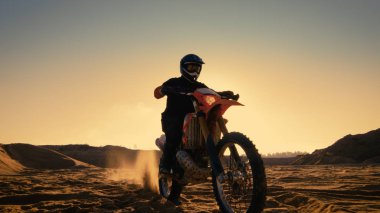 Düşük açılı Off-Road parça yolu üzerinde duran profesyonel motokros motosiklet binici bir kadeh. O gün batımı ve parça dumanla kaplı / sis.
